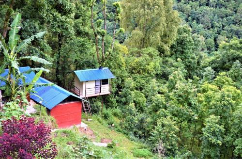 a small house with a blue roof on a hill at Jungle Crown Organic Homestay in Nagarkot