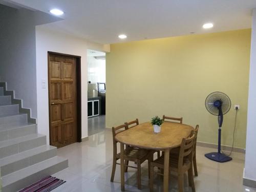 a dining room with a table and chairs and a fan at EJ Guesthouse in Cukai