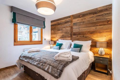une chambre avec un grand lit avec un mur en bois dans l'établissement JEANETTE 4, à Morzine