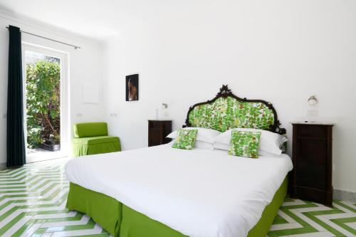 a white bedroom with a large bed and a green chair at Villa Massa Residence in Sant'Agnello