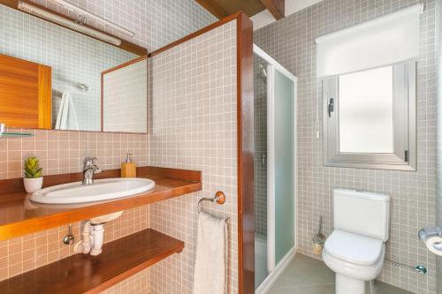 y baño con aseo, lavabo y espejo. en Villa Marta, en Es Mercadal