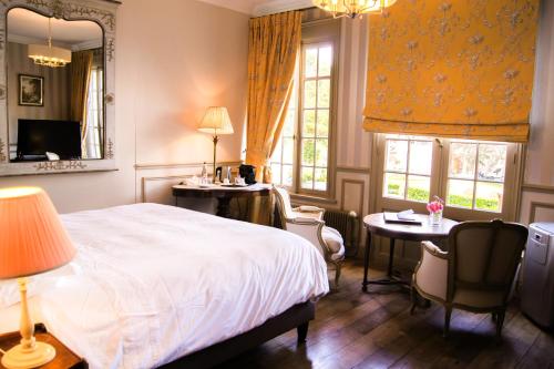 a bedroom with a bed and two tables and chairs at Le Manoir des Impressionnistes - Bord de Mer in Honfleur