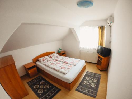 een kleine slaapkamer met een bed en een televisie bij Pensiunea Apolka Panzió in Covasna