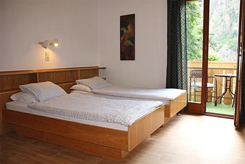 two beds in a bedroom with a balcony at Schlosshof Castello in Prato allʼIsarco