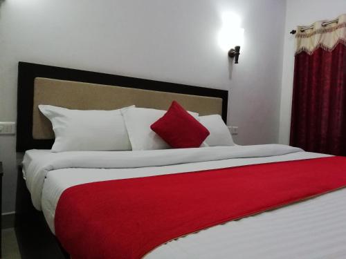 a bedroom with a large bed with a red blanket at Salisbury Manor Heritage Inn in Marayoor