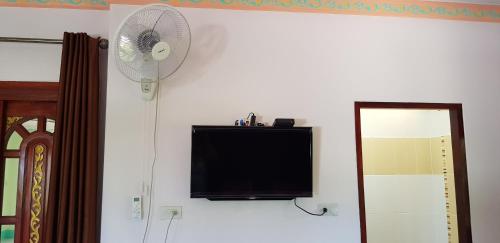 a flat screen tv on a wall with a fan at Khwahol Guesthouse in Don Sak