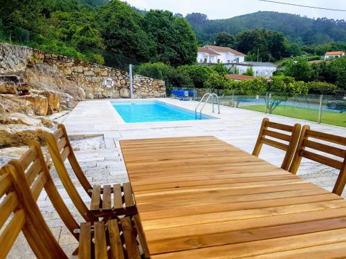 a wooden table with two chairs and a swimming pool at Cozy Villa Cristelo - Family & Friends in Cristelo