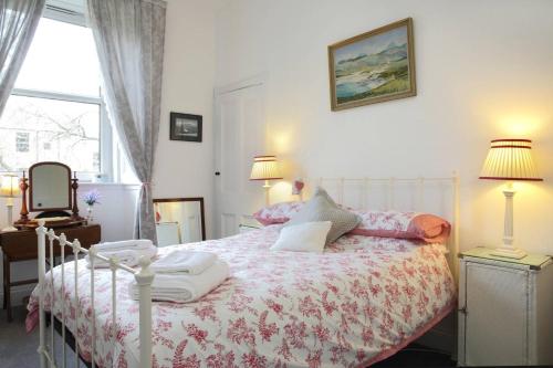 a bedroom with a bed with a pink and white comforter at 5 star beautiful & vintage, spacious apt in chic location! in Edinburgh