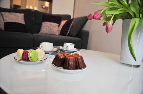 une table avec des assiettes de beignets et un vase avec des fleurs dans l'établissement Burdigala Homes - Appart Porte Basse, à Bordeaux