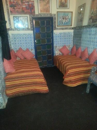 2 Betten in einem Zimmer mit roten und orangefarbenen Kissen in der Unterkunft RIAD DAR KADER chambre saumon in Marrakesch