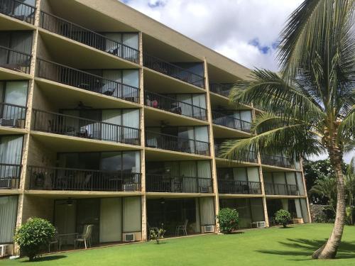an apartment building with balconies and a palm tree at Perfect for families and couples - Maui Sunset A-203 in Kihei