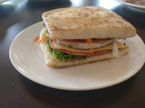 a sandwich on a white plate on a table at Pru Valley Thaley Tai Resort in Ban Don Phlap (1)