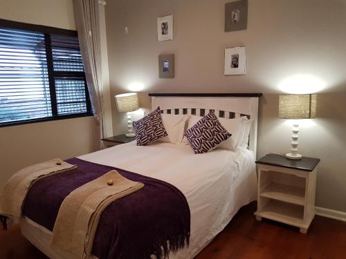 a bedroom with a white bed with pillows and a window at Bushys Oak in Bushmans River Village