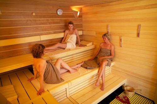 three women are sitting in a sauna at Romantik Hotel Waldschlösschen in Schleswig