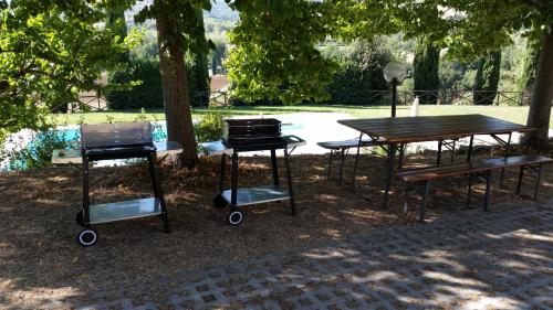 a group of picnic tables and a grill in a park at Case in campagna con piscina a Todi in Todi