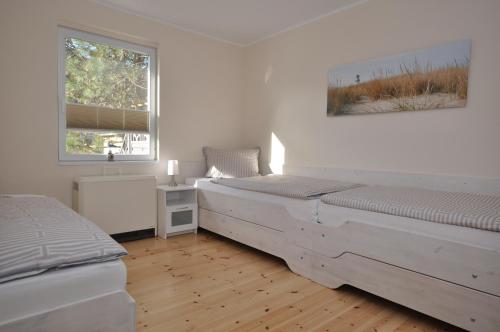 a white bedroom with two beds and a window at Steffchen EG in Pruchten