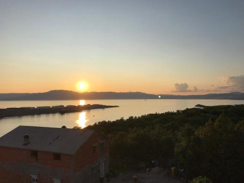 a sunset over a body of water with a building at Apartments Michael & Petra , Omisalj, Insel Krk, Kroatien in Omišalj