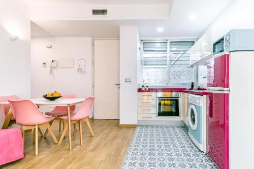 マラガにあるApartamentos Momas La Casa De Mamáのピンクの家電製品、テーブルと椅子付きのキッチンが備わります。