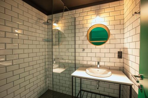 a white tiled bathroom with a sink and a mirror at Park Hotel Tsinandali Estate in Tsinandali
