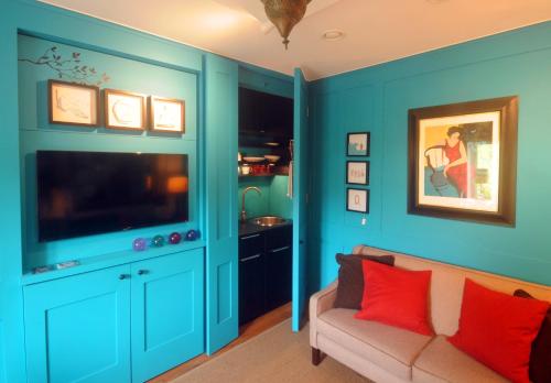 a blue living room with a couch and a tv at Mulberry cottage in Cheltenham