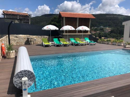 a swimming pool with chairs and umbrellas on a deck at Casa do Quinteiro in Carregosa