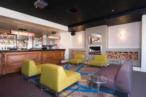 a waiting room with yellow chairs and a bar at Distinction Palmerston North Hotel & Conference Centre in Palmerston North