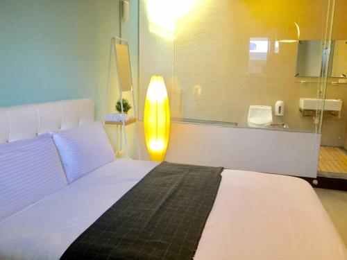 a bedroom with a white bed and a lamp at HSR B&B in Zhongli