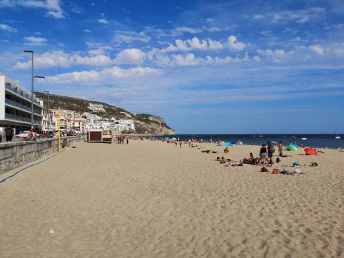 a group of people sitting on a beach at Home By The Sea in Sesimbra