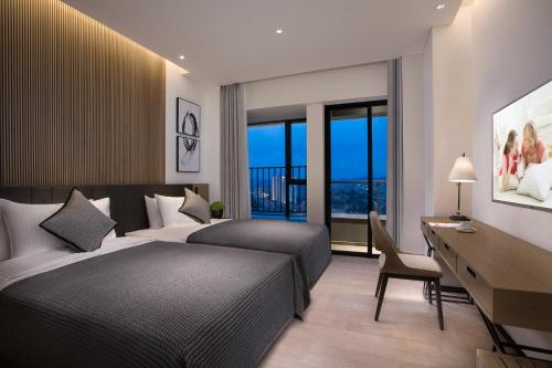 a hotel room with two beds and a desk and a desk at Citadines Songshan Lake Dongguan in Dongguan