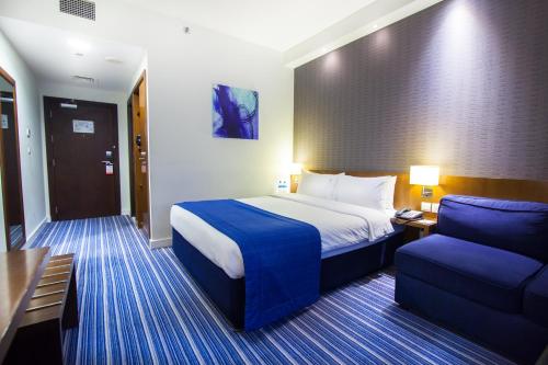 a hotel room with a bed and a blue chair at Holiday Bahrain Hotel in Manama