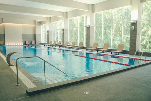 a large swimming pool with chairs in a building at Daina Jurmala Beach Hotel in Jūrmala