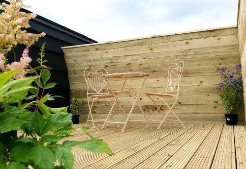 two chairs and a table on a wooden deck at Lilly's Lodges Orkney Butterfly Lodge in Finstown