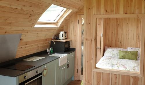 a small kitchen with a bed in a wooden cabin at Lilly's Lodges Orkney Butterfly Lodge in Finstown