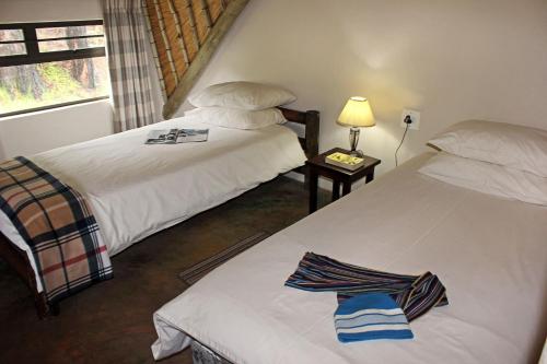 a bedroom with two beds and a table with a lamp at Sungubala Eco Camp in Bergville