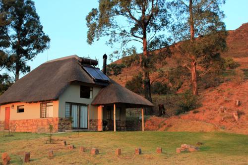 a small house with a thatched roof on a field at Sungubala Eco Camp in Bergville