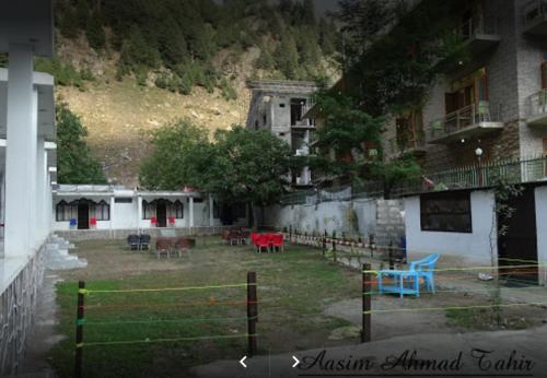 a yard with tables and chairs in front of a building at Flora Inn Hotel Naran in Nārān