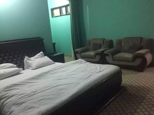 a hotel room with a bed and two chairs at Flora Inn Hotel Naran in Nārān