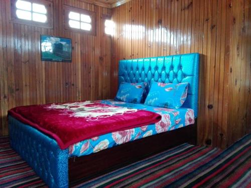 Ce lit bleu se trouve dans une chambre dotée de murs en bois. dans l'établissement Greenland Motel, à Mānsehra