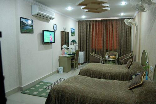 a hotel room with two beds and a desk at Hotel City View Peshawar in Peshawar
