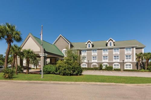 a large apartment building with palm trees and a street at Country Inn & Suites by Radisson, Beaufort West, SC in Beaufort