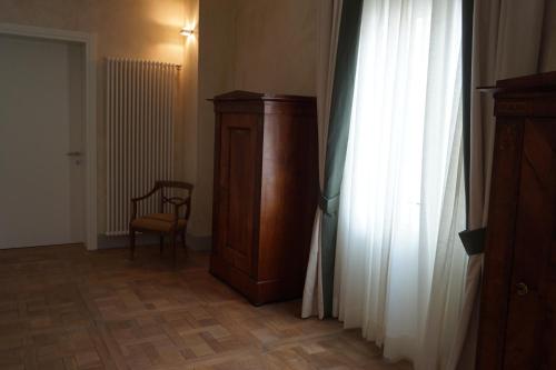 a room with a wooden cabinet and a chair next to a window at Palazzo Mantua Benavides Suites & Apartments in Padova