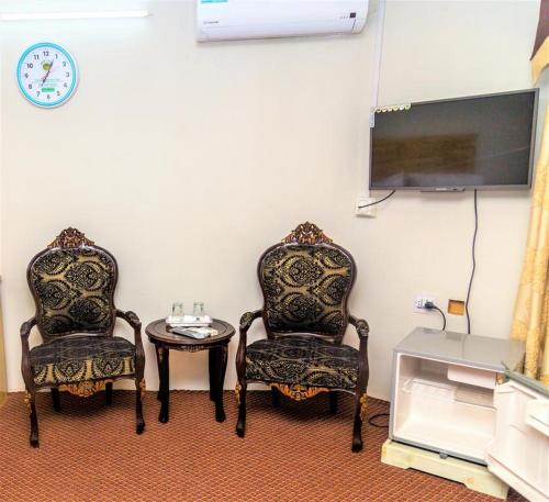 dwa krzesła i stół w pokoju z telewizorem w obiekcie Naveed Tourist Inn w mieście Gilgit