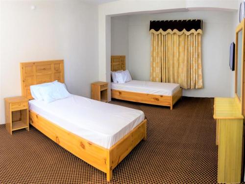 pokój z dwoma łóżkami i dwoma stołami w obiekcie Naveed Tourist Inn w mieście Gilgit