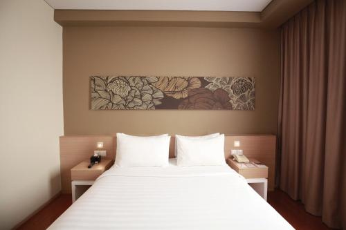 Un dormitorio con una cama blanca y una pintura en la pared en Swiss-Belinn Airport Jakarta, en Tangerang
