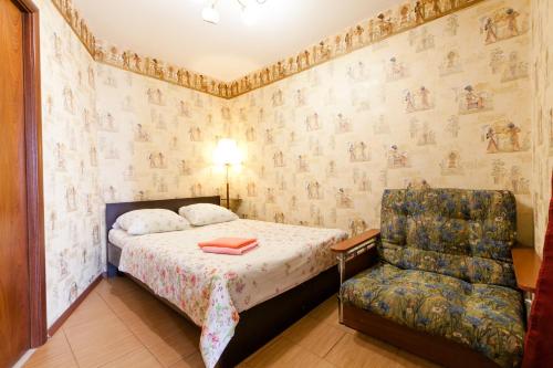 a bedroom with a bed and a chair at Центр! Папанинцев 111-157 in Barnaul