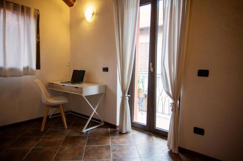 a room with a desk with a laptop and a window at Piccola casa vacanze - Small vacation house in Porto Valtravaglia