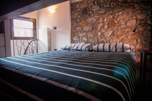 a bed in a room with a stone wall at Piccola casa vacanze - Small vacation house in Porto Valtravaglia