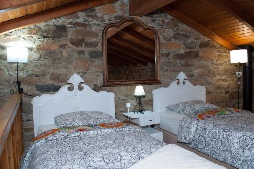 um quarto com 2 camas e uma parede de pedra em Azoka by the River- Proença-a-Nova em Maljoga de Proença