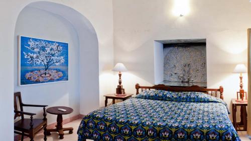 a bedroom with a bed and a painting on the wall at Neemrana's - Tijara Fort Palace in Alwar