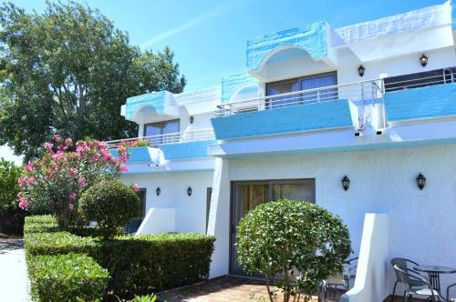 a white building with a blue balcony and some bushes at Blue Horizon in Ialyssos